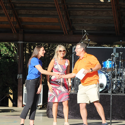 2 CFB employees shaking hands with event staff on the stage of the Cool Creek Concert.